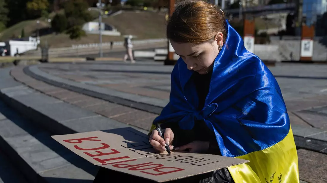 Eine Studentin in Kiew schreibt die ersten Worte des ukrainischen Gedichts «Kämpfe weiter - du wirst siegen» von Taras Schewtschenko auf ein Plakat. - Bild: Alex Babenko/AP/dpa