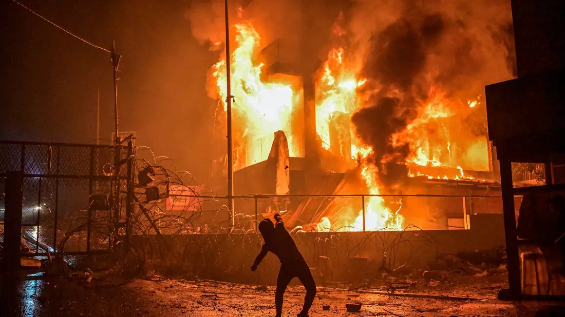 Ein Demonstrant wirft nach dem Angriff auf das Krankenhaus im Gazastreifen Steine auf ein brennendes Gebäude in der Nähe der US-Botschaft in Beirut. - Bild: Stringer/dpa