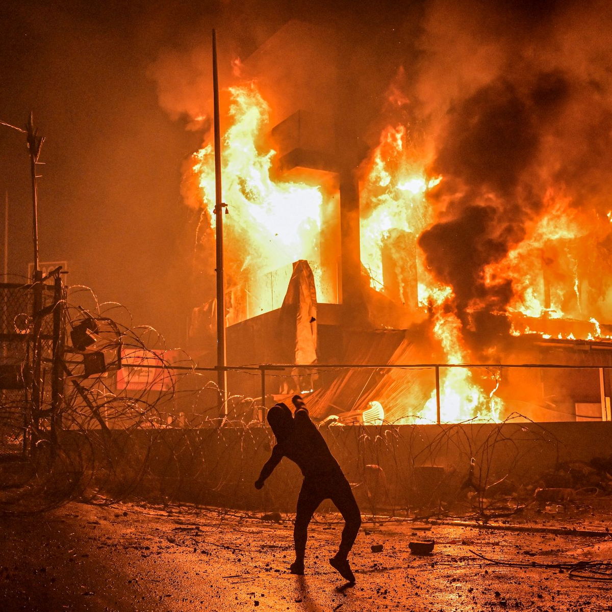 Ein Demonstrant wirft nach dem Angriff auf das Krankenhaus im Gazastreifen Steine auf ein brennendes Gebäude in der Nähe der US-Botschaft in Beirut. - Foto: Stringer/dpa