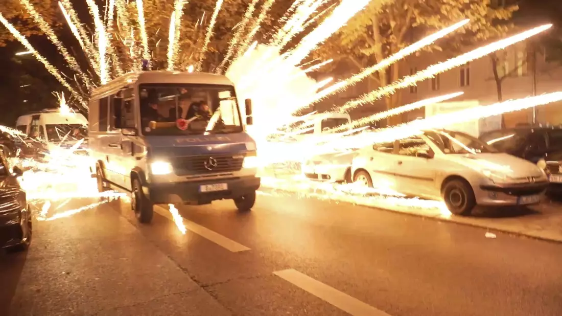 Feuerwerkskörper fliegen hinter einem Polizeiauto bei einer nicht angekündigten pro-palästinensischen Demonstration in Neukölln. - Bild: -/TNN/dpa