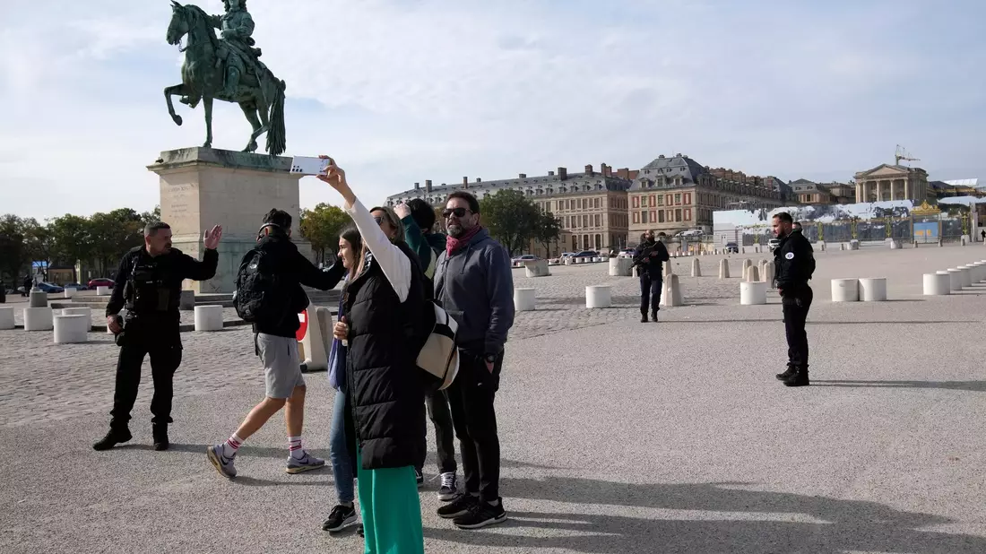 Touristen warten, während französische Polizisten das Schloss von Versailles nach einem Sicherheitsalarm bewachen. - Bild: Christophe Ena/AP/dpa