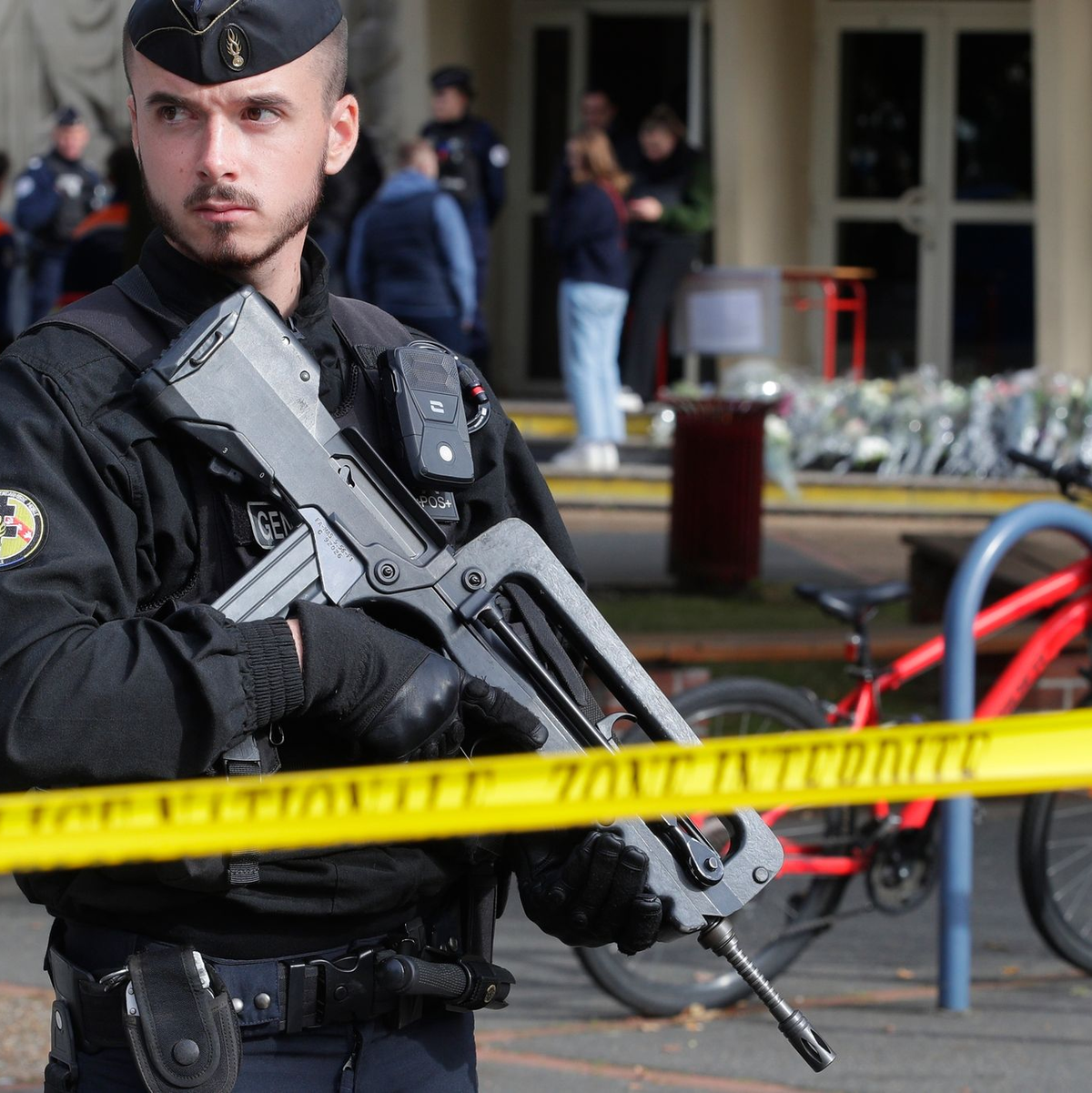 Ein schwer bewaffneter französischer Polizist vor einem Gymnasium (Archivbild). In Frankreich häufen sich seit einigen Tagen Bombendrohungen, insbesondere gegen Schulen - nun gibt es auch welche gegen mehrere Regionalflughäfen. - Foto: Michel Spingler/AP/dpa