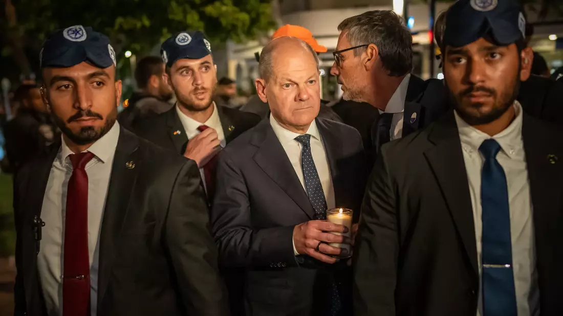 Bundeskanzler Olaf Scholz, umringt von Bodyguards, bei seinem Solidaritätsbesuch in Israel mit einer Kerze in der Hand am Dizengoff Square im Zentrum von Tel Aviv. - Bild: Michael Kappeler/dpa Pool/dpa