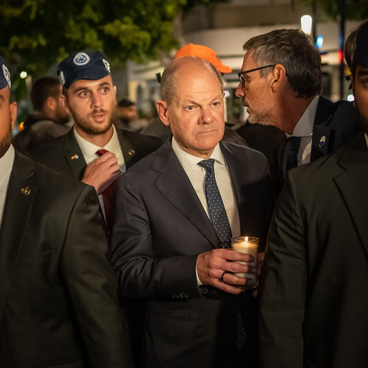Bundeskanzler Olaf Scholz, umringt von Bodyguards, bei seinem Solidaritätsbesuch in Israel mit einer Kerze in der Hand am Dizengoff Square im Zentrum von Tel Aviv. - Foto: Michael Kappeler/dpa Pool/dpa