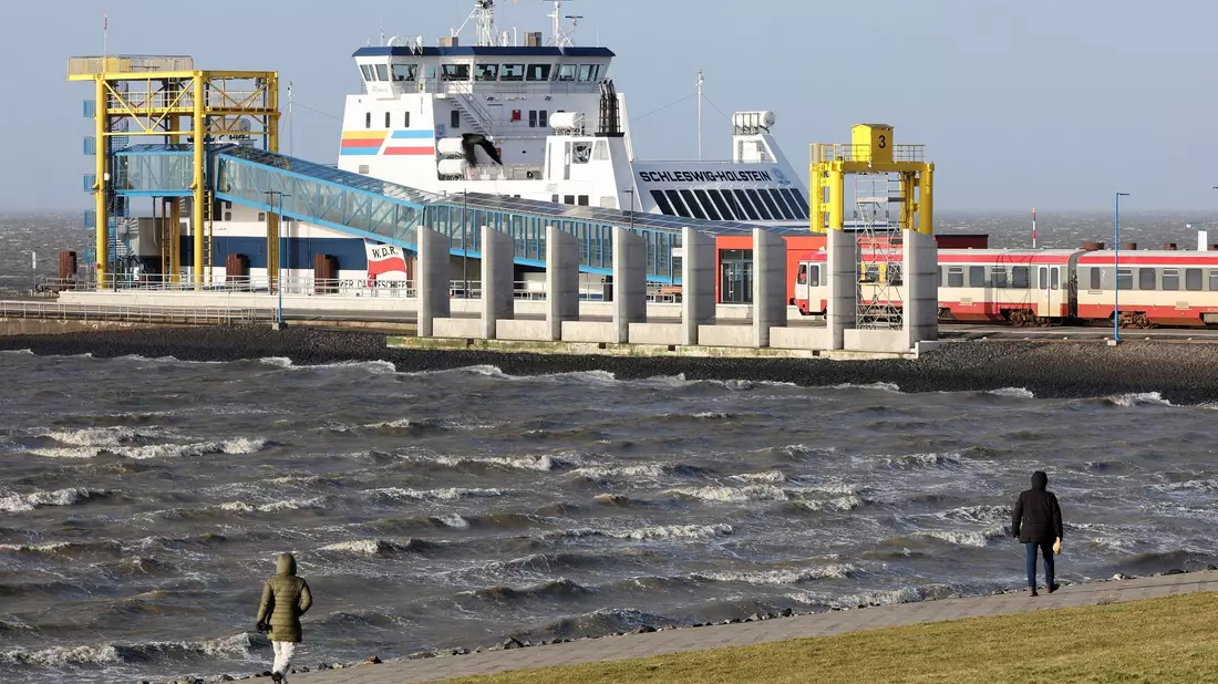 Spaziergänger sind bei stürmischem Wetter am Hafen von Dagebüll unterwegs. (Archivbild) - Bild: Bodo Marks/dpa