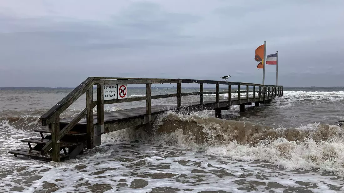 Ein Badesteg in Niendorf wird von Wellen umspült. An der schleswig-holsteinischen Ostseeküste wird eine schwere Sturmflut erwartet. - Bild: Thomas Müller/dpa