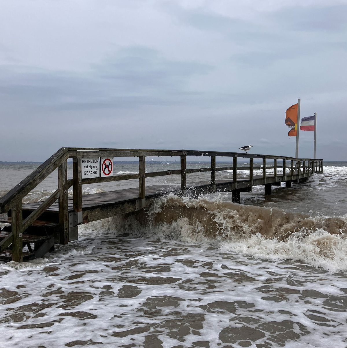 Ein Badesteg in Niendorf wird von Wellen umspült. An der schleswig-holsteinischen Ostseeküste wird eine schwere Sturmflut erwartet. - Foto: Thomas Müller/dpa