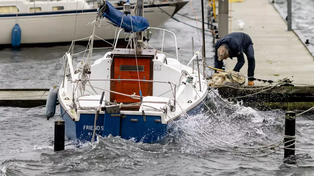Ein Mann sichert ein Segelboot an einem Anlegesteg in der Kieler Förde. - Bild: Axel Heimken/dpa