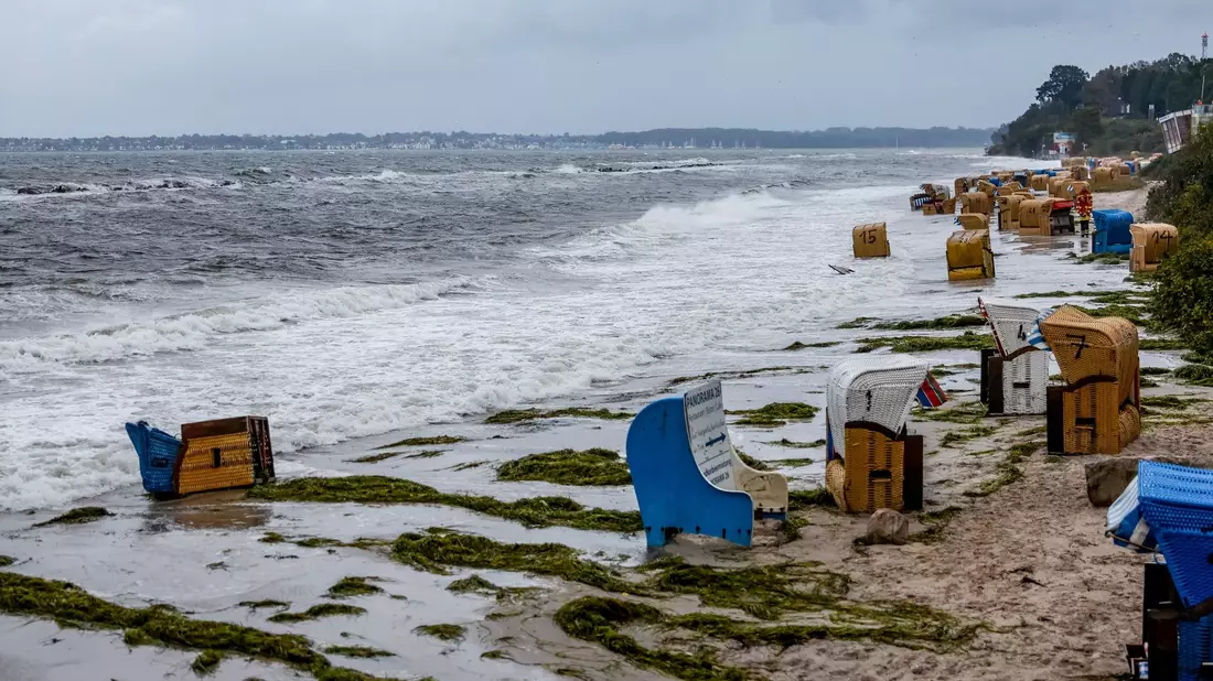 Einsatzkräfte der Feuerwehr sichern in  in Kiel-Schiksee Strandkörbe vor den Flutwellen der Ostsee. - Bild: Axel Heimken/dpa
