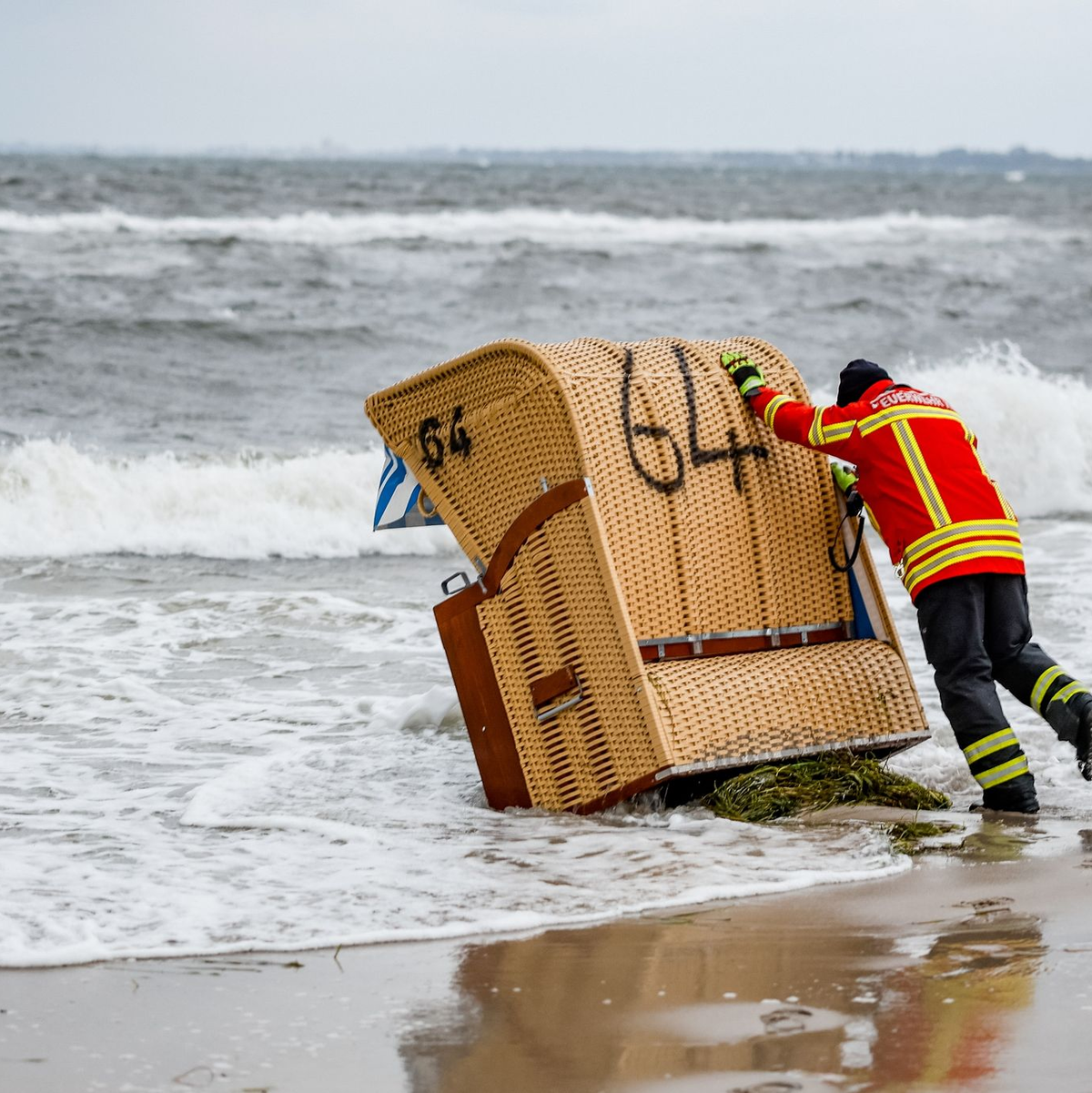 Ein Feuerwehrmann versucht, in Kiel-Schiksee einen Strandkorb vor den Flutwellen der Ostsee zu sichern. - Foto: Axel Heimken/dpa