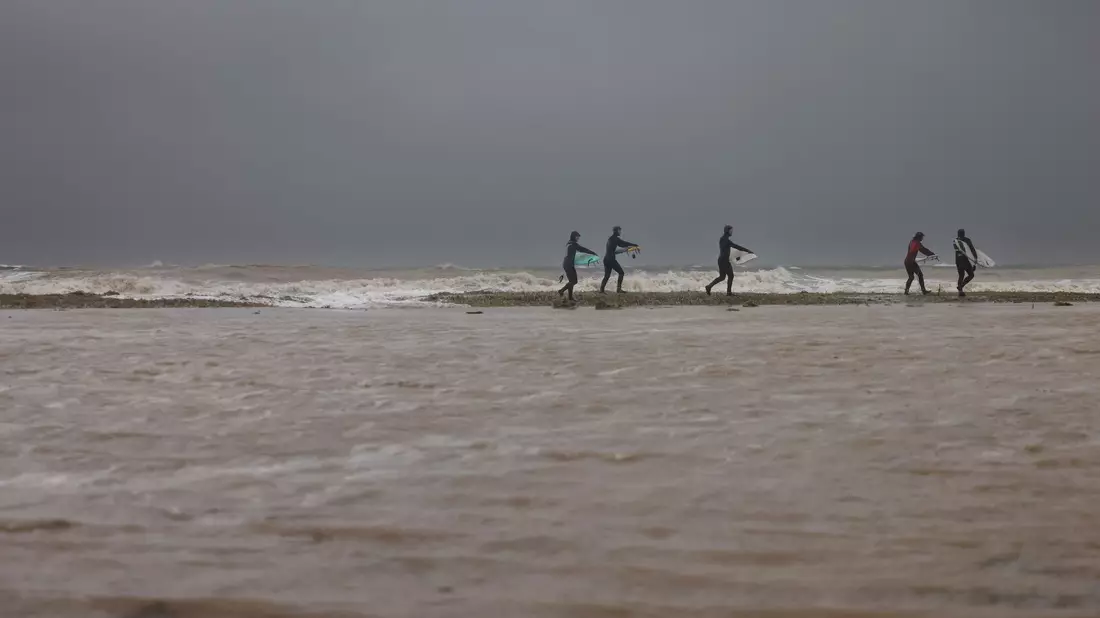 Surfer gehen über den überfluteten Ostseestrand in Eckernförde zum Meer. - Bild: Frank Molter/dpa