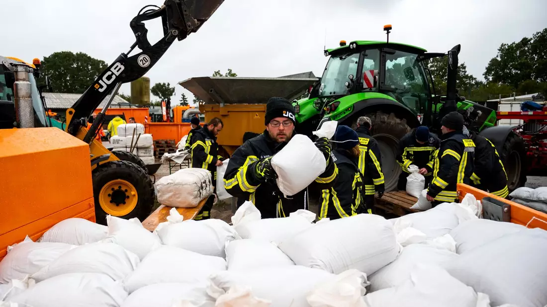 Feuerwehrleute füllen in Grömitz in Ostholstein Sandsäcke. - Bild: Daniel Bockwoldt/dpa