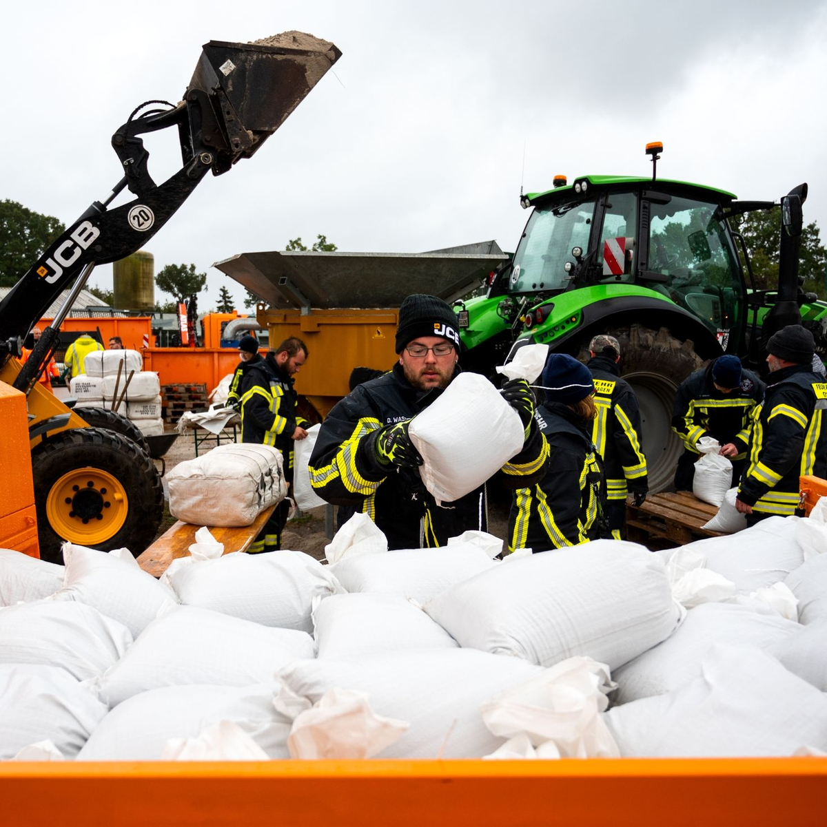 Feuerwehrleute füllen in Grömitz in Ostholstein Sandsäcke. - Foto: Daniel Bockwoldt/dpa