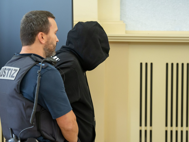 Der Angeklagte (r) wird vor Prozessbeginn in den Gerichtssaal gebracht. Gegen ihn wurde eine lebenlange Haftstrafe verhängt. - Foto: Silas Stein/dpa