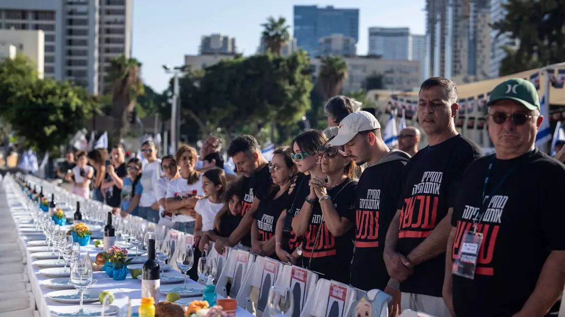 Angehörige von Menschen, die von Hamas-Kämpfern entführt wurden, beten in Tel Aviv umgeben von 203 leeren Stühlen. - Bild: Petros Giannakouris/AP/dpa