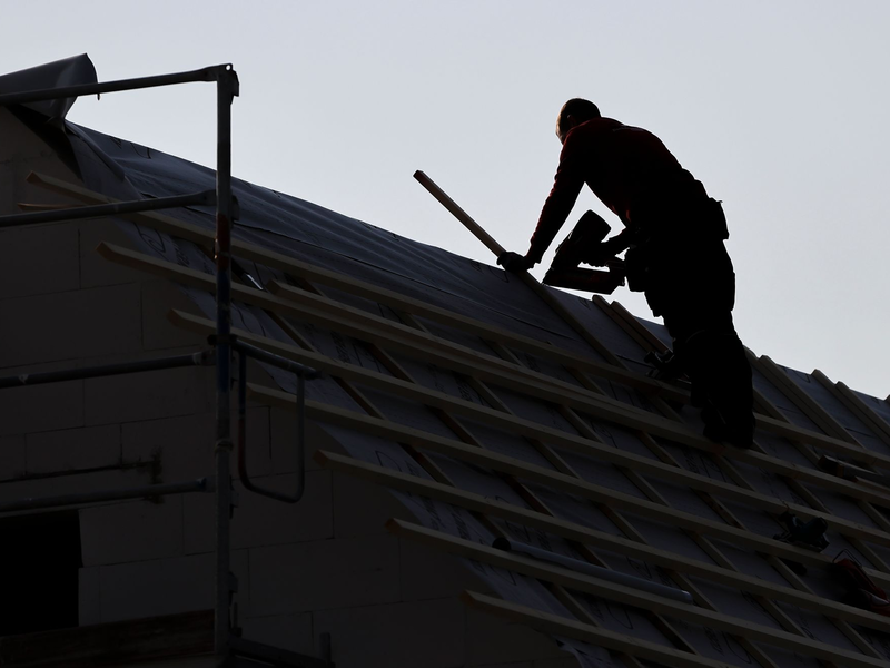 Ein Dachdecker arbeitet auf einem Einfamilienhaus. - Foto: Jan Woitas/dpa