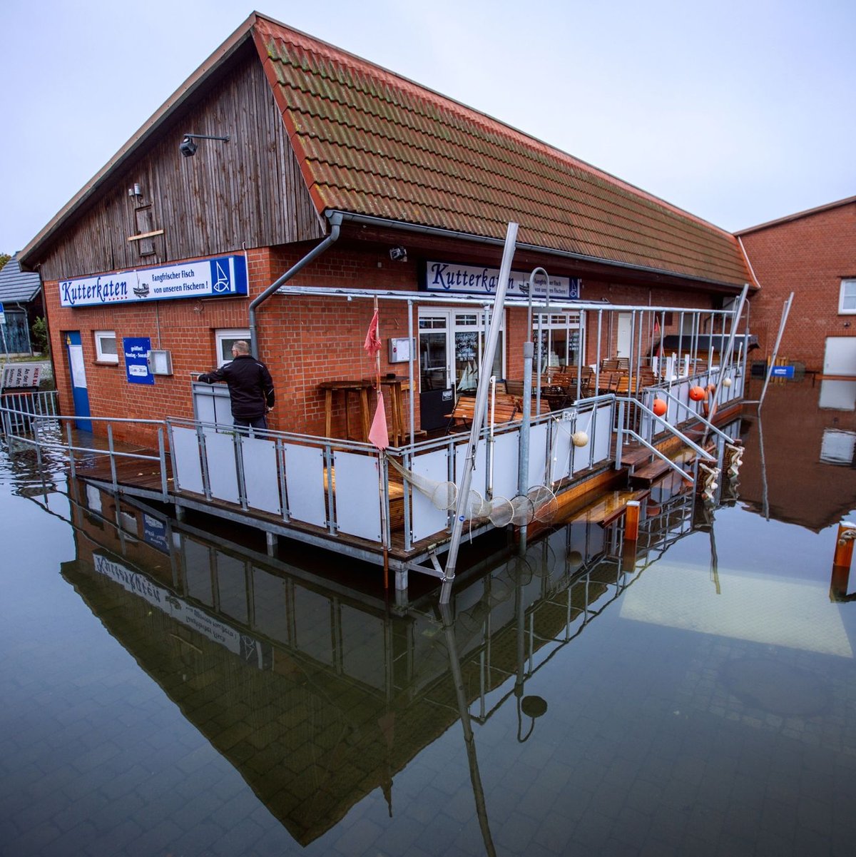 Fahrräder stehen an einer überfluteten Straßenkreuzung in der Nähe des Fischereihafens in Wismar im Wasser. - Foto: Jens Büttner/dpa