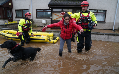 Ein Rettungsmitarbeiter hilft einer  Bewohnerin aus einem Haus, während der Sturm «Babet» über das Land fegt. - Foto: Andrew Milligan/PA Wire/dpa