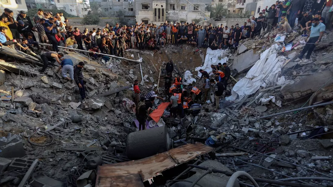 Palästinenser versammeln sich vor den Überresten eines zerstörten Hauses in Gaza-Stadt. - Bild: Abed Khaled/AP/dpa