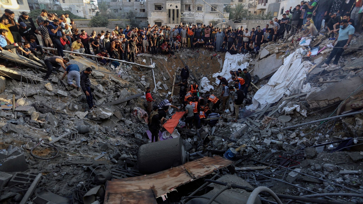 Palästinenser versammeln sich vor den Überresten eines zerstörten Hauses in Gaza-Stadt. - Foto: Abed Khaled/AP/dpa