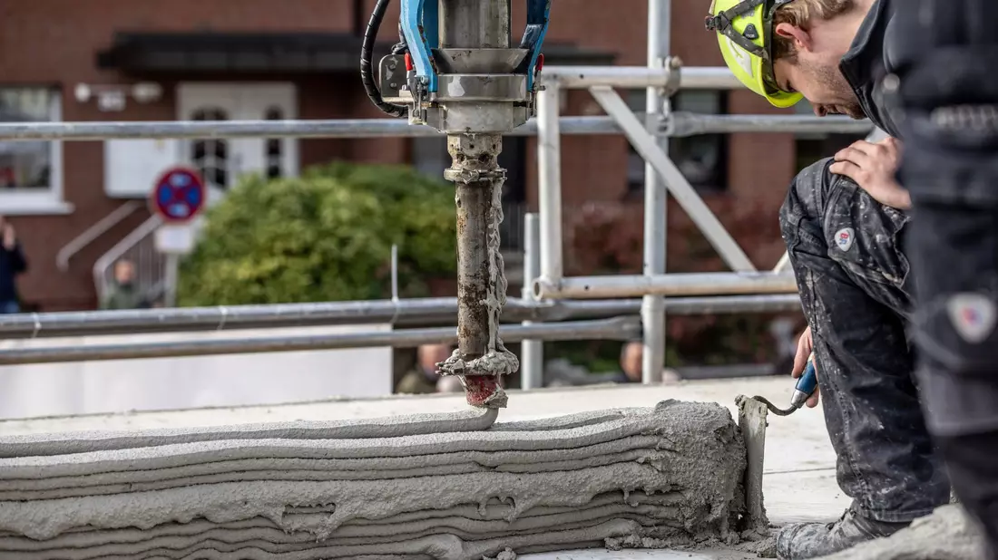 Ein Arbeiter inspiziert die Baustelle eines Mehrfamilienhauses aus dem 3D-Drucker. - Bild: Dieter Menne/dpa