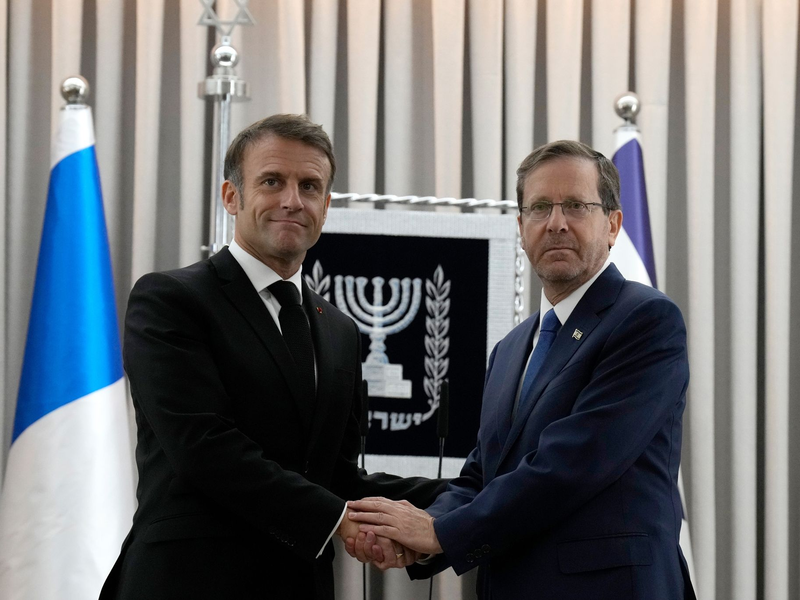 Emmanuel Macron (l), Präsident von Frankreich, schüttelt Izchak Herzog, Präsident von Israel, die Hand. Frankreichs Präsident Macron ist zu einem zweitägigem Besuch in Israel. - Foto: Christophe Ena/AP Pool/dpa