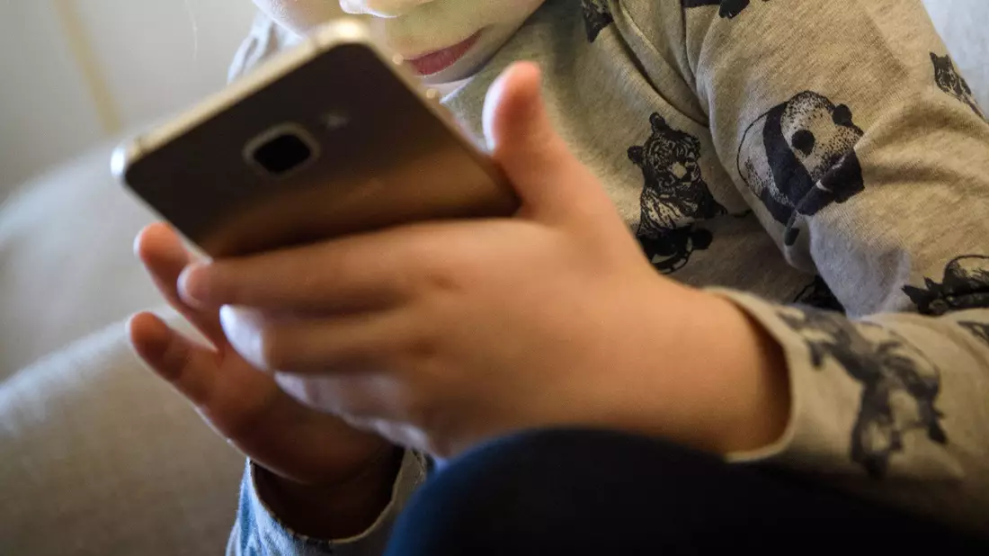 Ein kleines Mädchen schaut auf das Display eines Smartphones. Dutzende US-Bundesstaaten ziehen gegen den Facebook-Konzern Meta vor Gericht. Sie werfen dem Unternehmen vor negative Folgen für Kinder und Jugendliche zu ignorieren, um mehr Gewinn zu machen. - Bild: Hans-Jürgen Wiedl/ZB/dpa