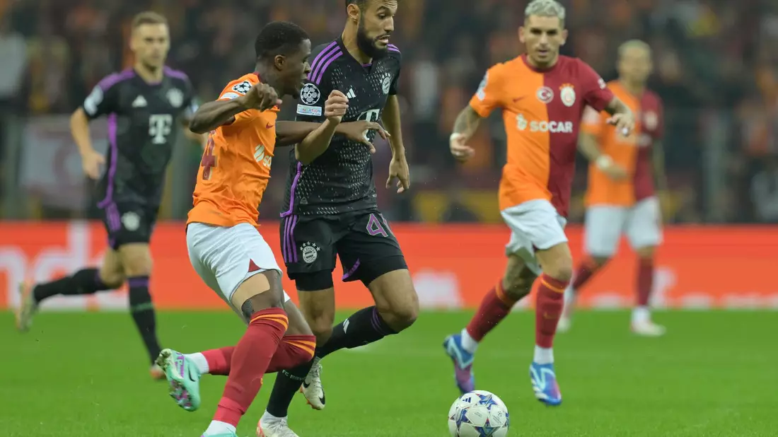 Noussair Mazraoui vom FC Bayern München (M) im Duell mit Wilfried Zaha von Galatasaray Istanbul. - Bild: Peter Kneffel/dpa