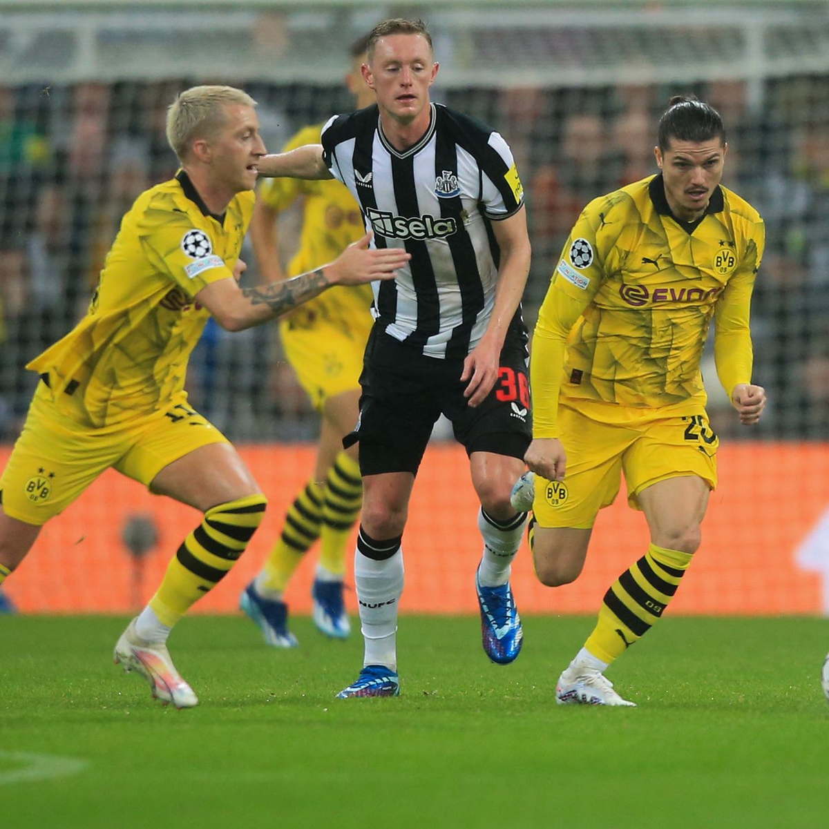 Marco Reus (l) und Marcel Sabitzer (r) doppeln Newcastles Sean Longstaff. - Foto: Lindsey Parnaby/dpa