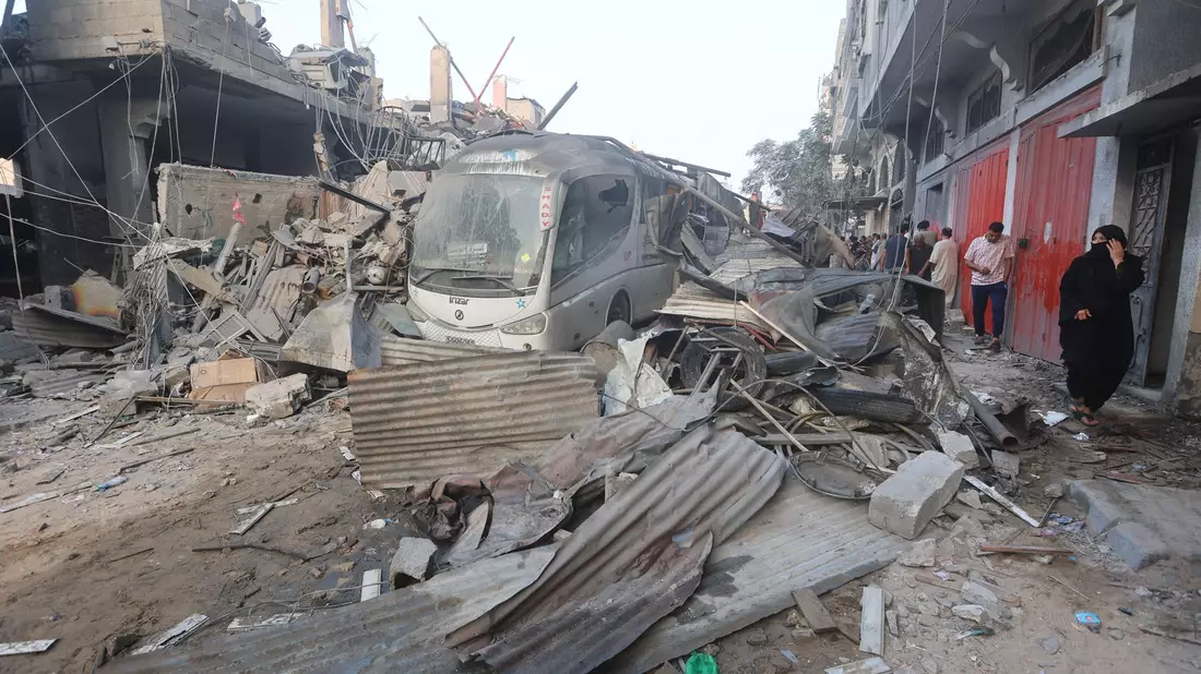 Eine palästinensische Frau geht durch die Trümmer eines Gebäudes, das bei einem israelischen Luftangriff im Gazastreifen getroffen wurde. - Bild: Ahmed Zakot/SOPA Images via ZUMA Press Wire/dpa