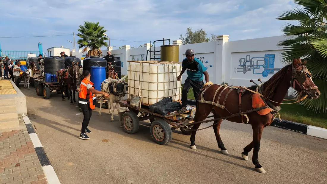 Palästinenser stehen Schlange, um Trinkwasser aus einer Wasseraufbereitungsanlage zu holen. - Bild: Hassan Eslaiah/AP/dpa