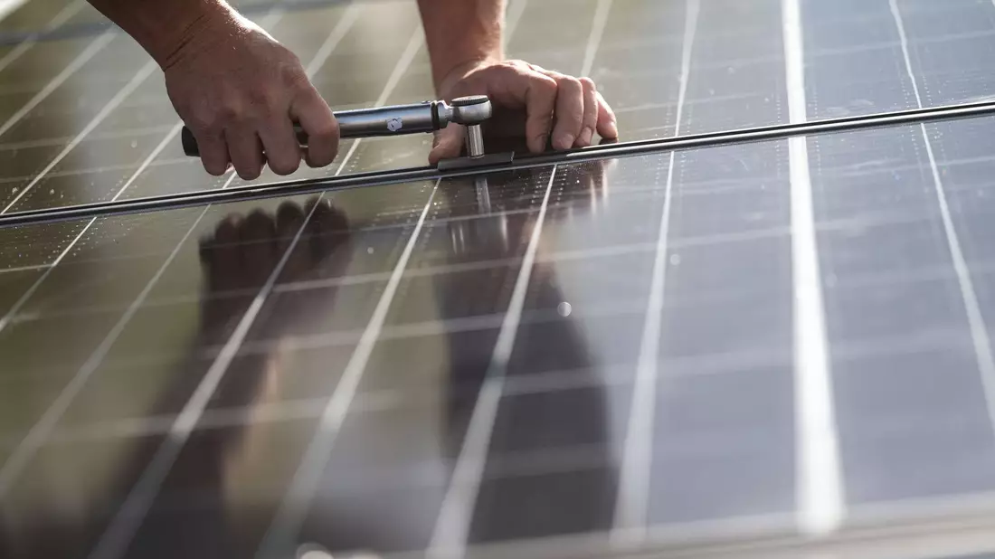 Fachkräfte montieren Photovoltaikmodule auf dem Dach eines Wohnhauses in Stuttgart. - Bild: Marijan Murat/dpa