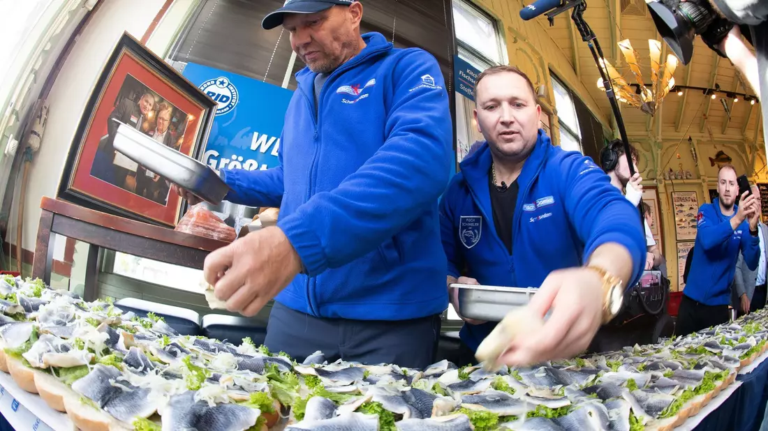 Axel Schulz, ehemalige Profiboxer (l-r), und André Domke, Fischsommelier und -händler, belegen das gigantische Fischbrötchen mit Salat, Fisch und Zwiebeln. - Bild: Stefan Sauer/dpa
