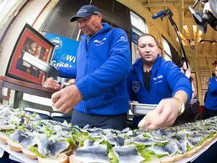 Axel Schulz, ehemalige Profiboxer (l-r), und André Domke, Fischsommelier und -händler, belegen das gigantische Fischbrötchen mit Salat, Fisch und Zwiebeln. - Foto: Stefan Sauer/dpa