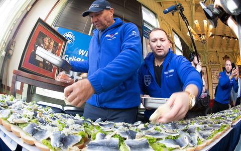 Axel Schulz, ehemalige Profiboxer (l-r), und André Domke, Fischsommelier und -händler, belegen das gigantische Fischbrötchen mit Salat, Fisch und Zwiebeln. - Foto: Stefan Sauer/dpa