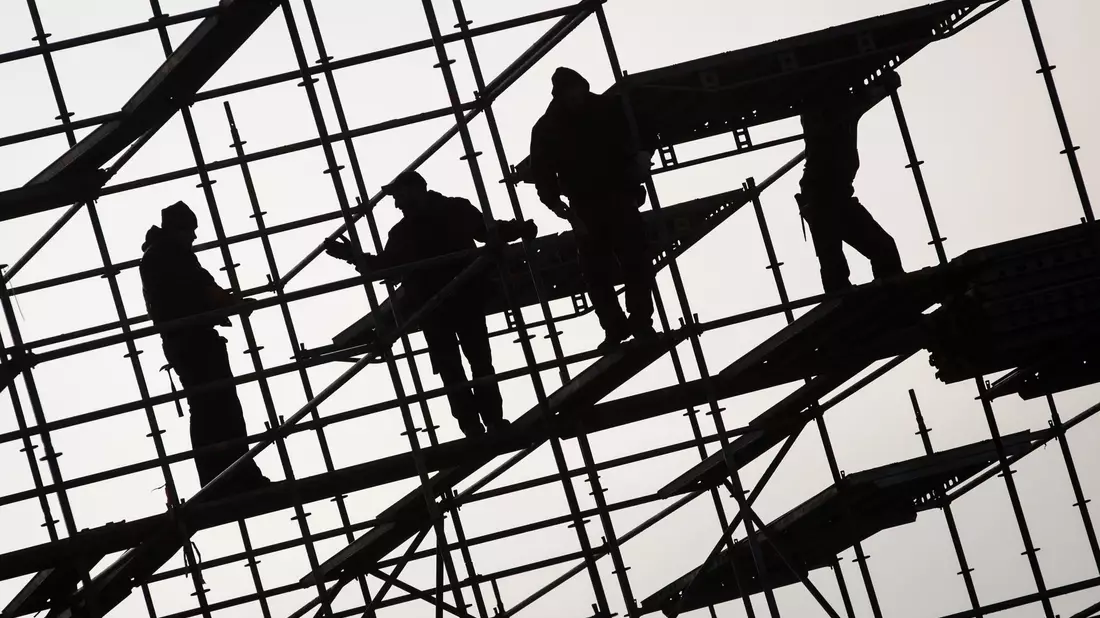 Gerüstbauer errichten ein Gerüst. Die hohe Teuerungsrate und die schwächere Konjunktur dürften die Schwarzarbeit in Deutschland spürbar anheizen. (Symbolbild) - Bild: Christian Charisius/dpa