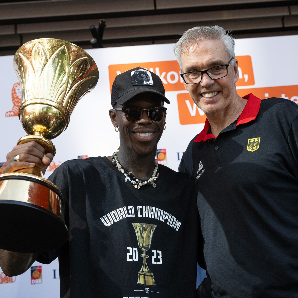 Dennis Schröder (l) und Basketball-Bundestrainer Gordon Herbert mit dem WM-Pokal. - Foto: Boris Roessler/dpa