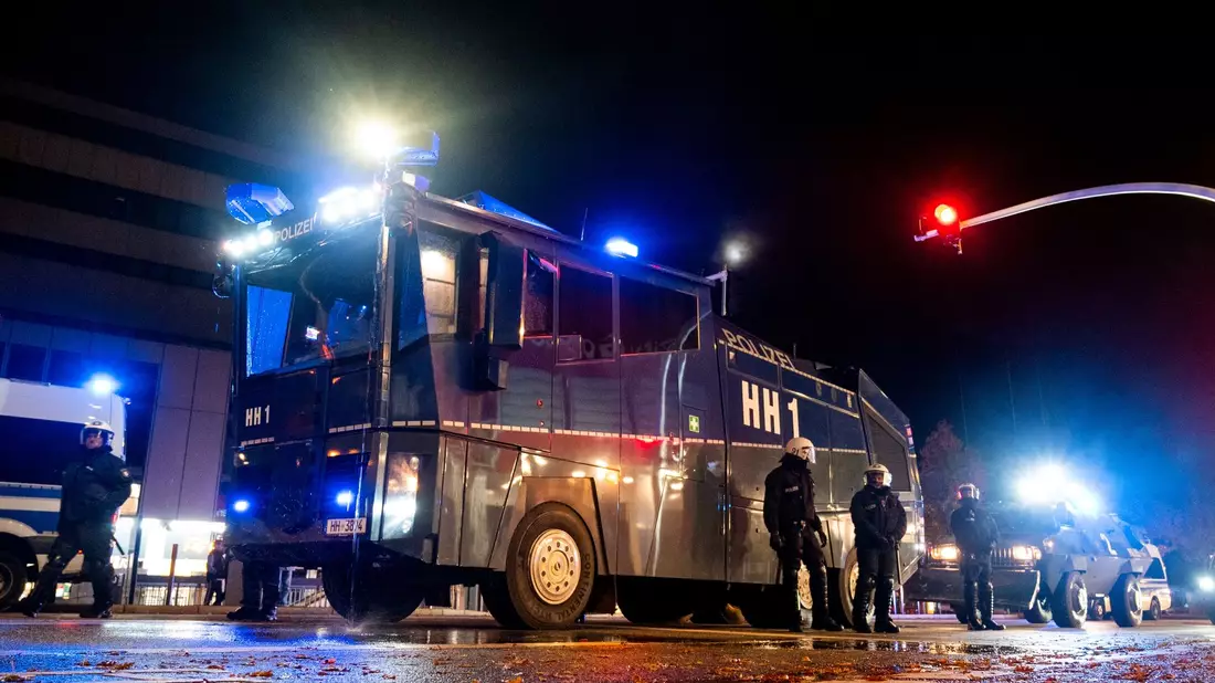 Ein Wasserwerfer der Polizei steht im Stadtteil Harburg bereit. In der Halloween-Nacht ist es in Hamburg zu Ausschreitungen gekommen. - Bild: Daniel Bockwoldt/dpa/Daniel Bockwoldt