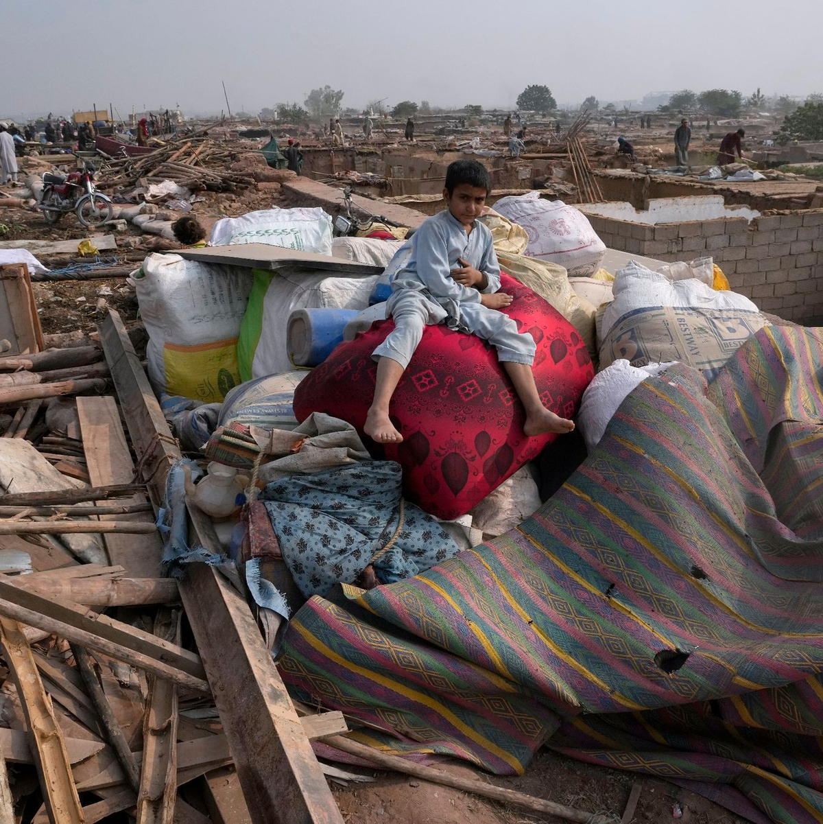 Ein afghanischer Junge sitzt auf den Habseligkeiten seiner Familie, die aus beschädigten Lehmhäusern geholt wurden. - Foto: Anjum Naveed/AP/dpa