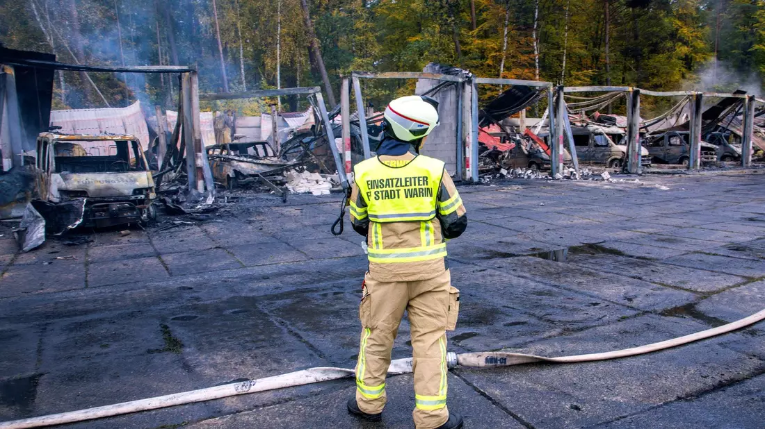 Feuerwehrleute löschen letzte Brandherde nach einem Feuer auf dem Gelände der Feuerwehr in Warin. - Bild: Jens Büttner/dpa