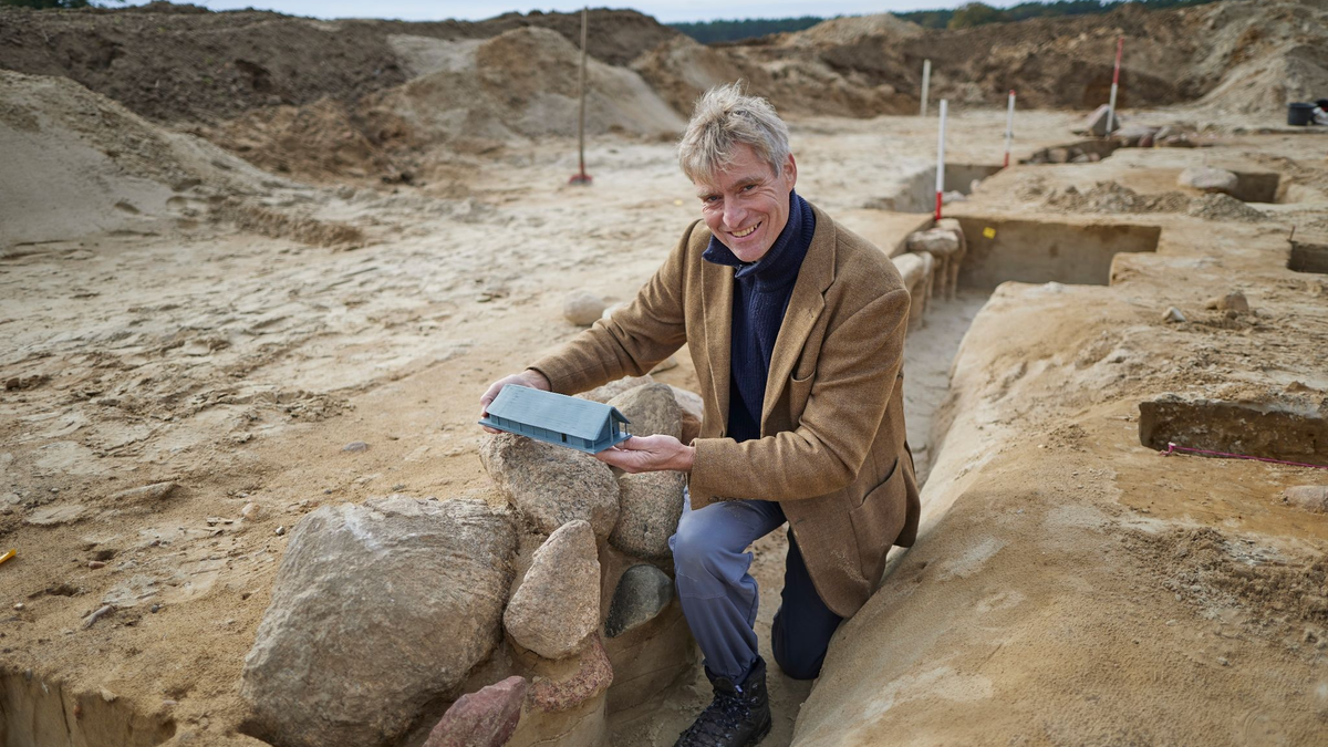 Der Grabungsleiter Immo Heske zeigt ein Modell der Versammlungshalle. - Foto: Joerg Carstensen/dpa