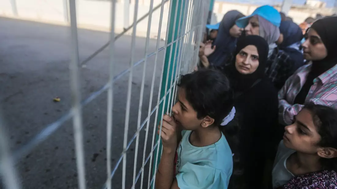 Menschen warten vor einem Zaun am Grenzübergang zwischen dem Gazastreifen und Ägypten. - Bild: Mohammed Talatene/dpa