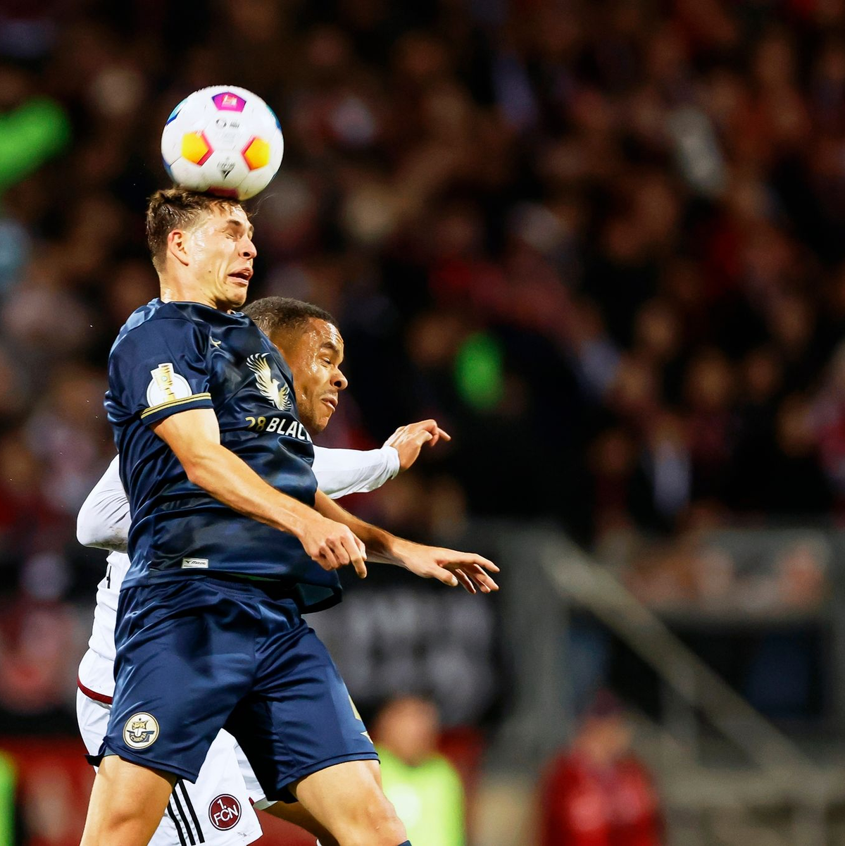 Rostocks Alexander Rossipal (vorn) im Kopfballduell mit dem Nürnberger Jan Gyamerah. - Foto: Daniel Löb/dpa