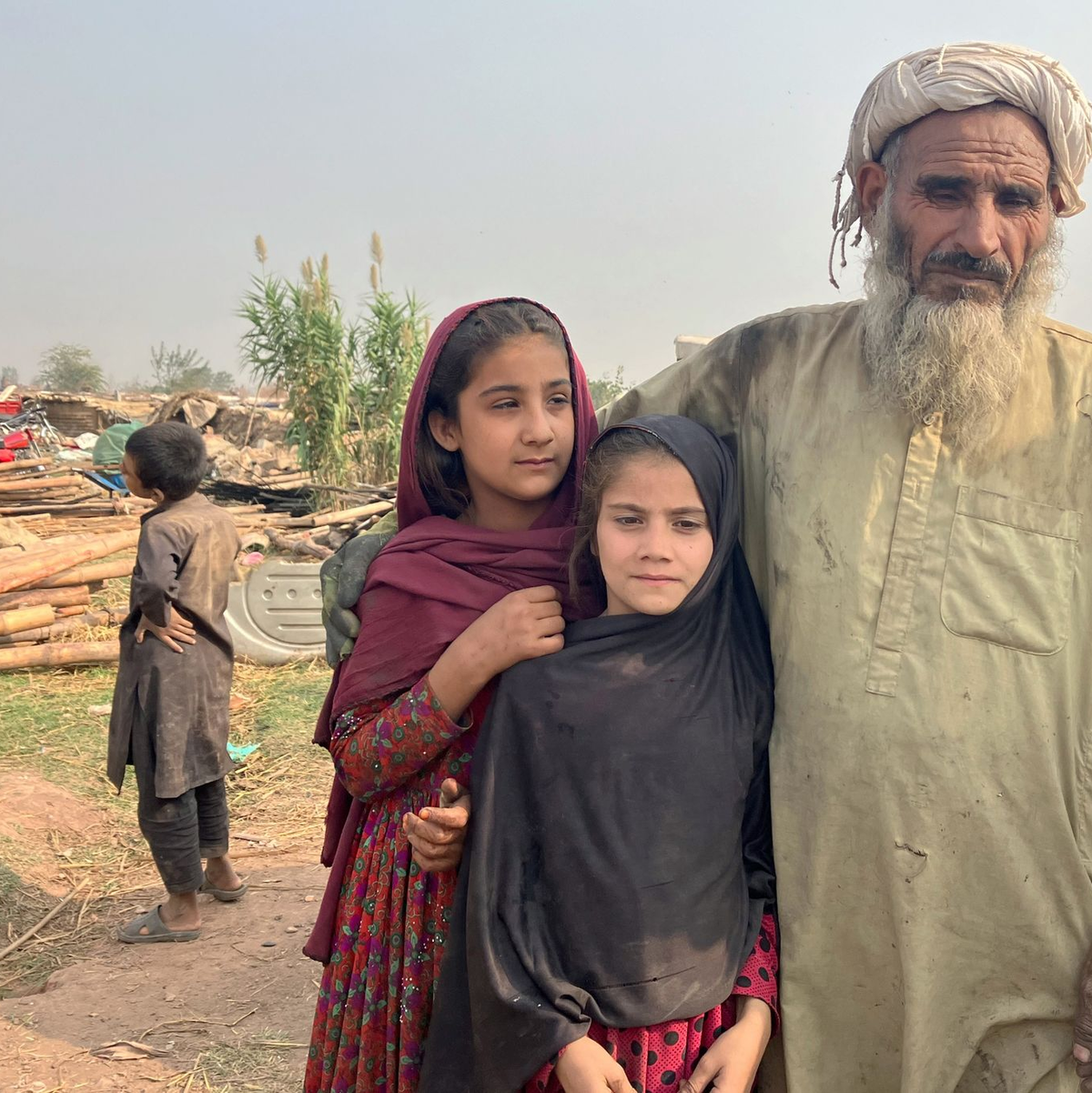 Ein afghanischer Vater und seine Töchter stehen zwischen den Überresten eines Flüchtlingslagers am Stadtrand von Islamabad, das von Bulldozern abgerissen wurde. - Foto: Nabila Lalee/dpa