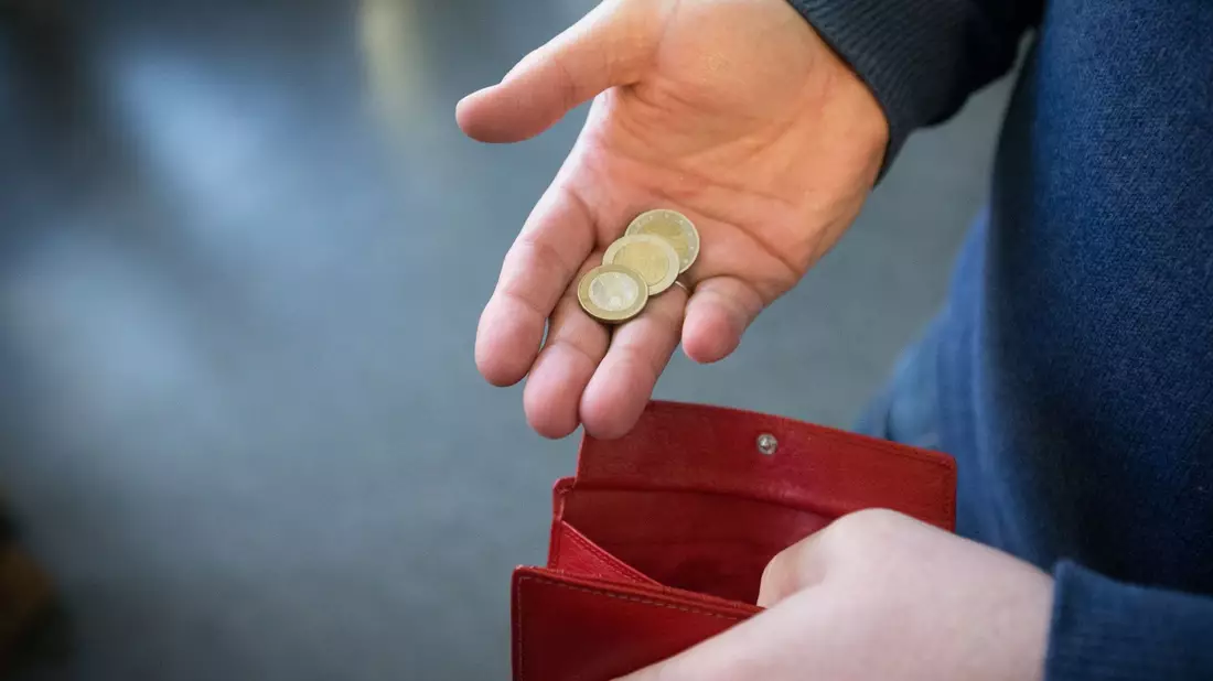 ILLUSTRATIOMünzen im Wert von fünf Euro liegen in einer Hand über einem Portemonnaie. - Bild: Friso Gentsch/dpa