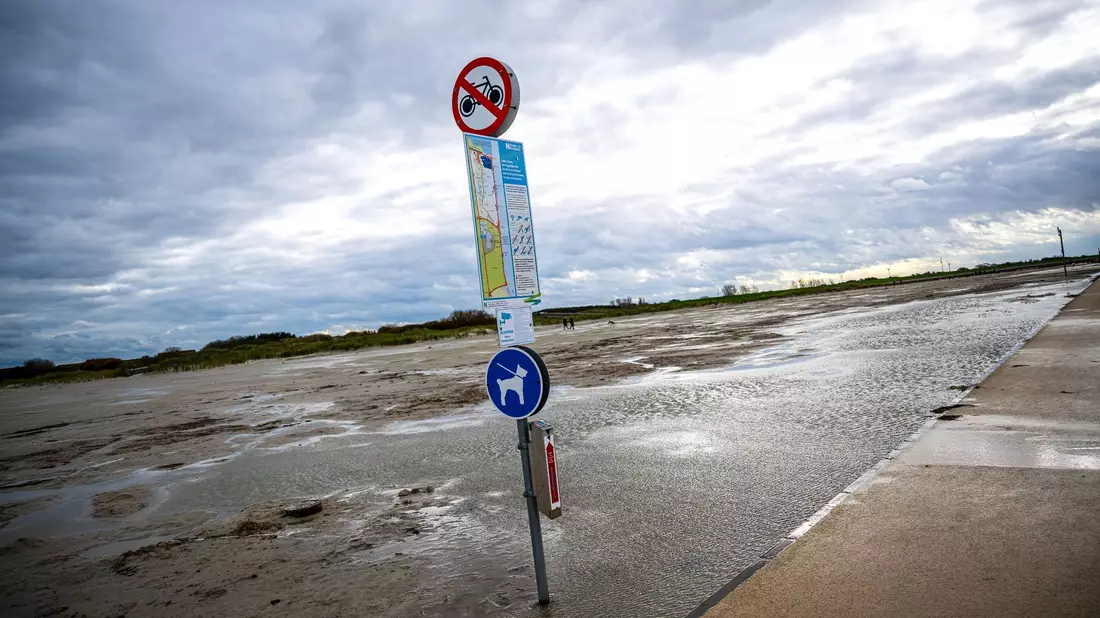 Dunkle Wolken ziehen über den Strand von Norddeich. - Bild: Sina Schuldt/dpa
