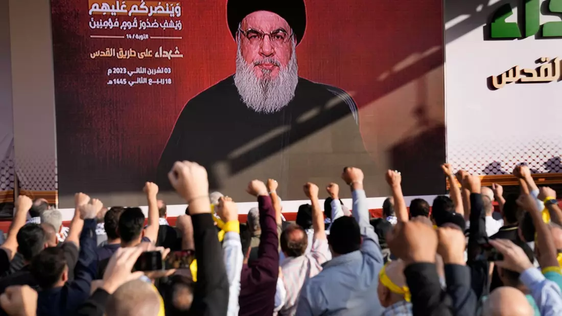 Anhänger der vom Iran unterstützten Hisbollah erheben in Beirut ihre Fäuste und jubeln, als Hisbollah-Führer Hassan Nasrallah während einer Kundgebung zum Gedenken an in den vergangenen Wochen getötete Hisbollah-Kämpfer über eine Videoverbindung erscheint. - Bild: Hussein Malla/AP