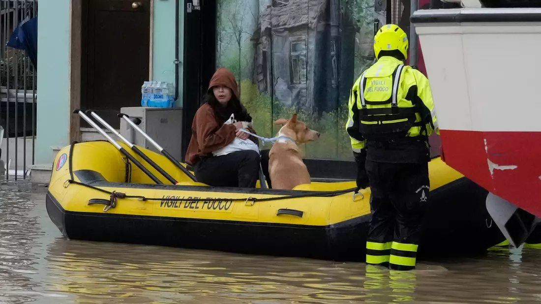 Feuerwehrleute retten eine Anwohnerin und ihren Hund im Ort Campi di Bisenzio. - Bild: Gregorio Borgia/AP/dpa