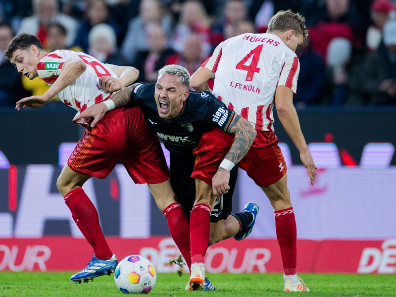 Die Kölner Eric Martel (l) und Timo Hübers (r) nehmen Augsburgs Philipp Tietz in die Zange. - Foto: Rolf Vennenbernd/dpa