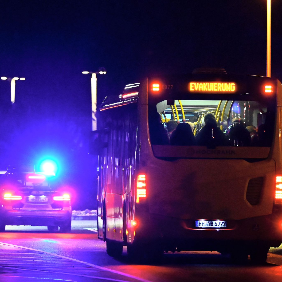 Ein Polizeiauto eskortiert einen Bus mit Menschen vom Flughafen Hamburg. - Foto: Jonas Walzberg/dpa